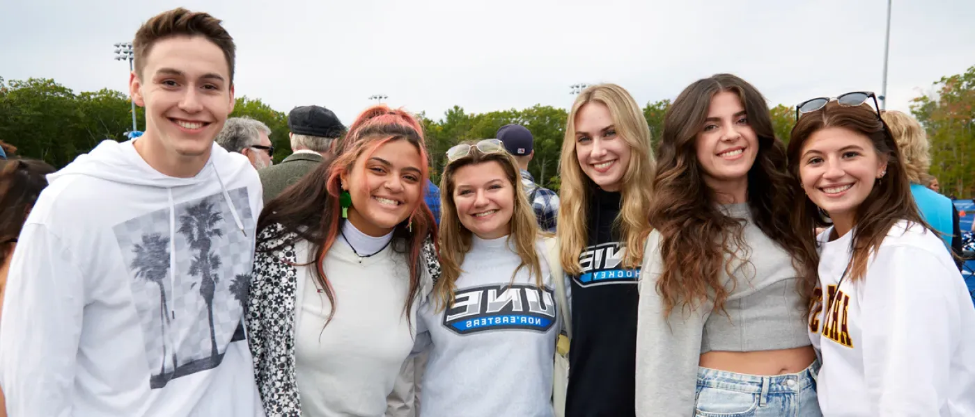 Several students standing together at a U N E Homecoming football game